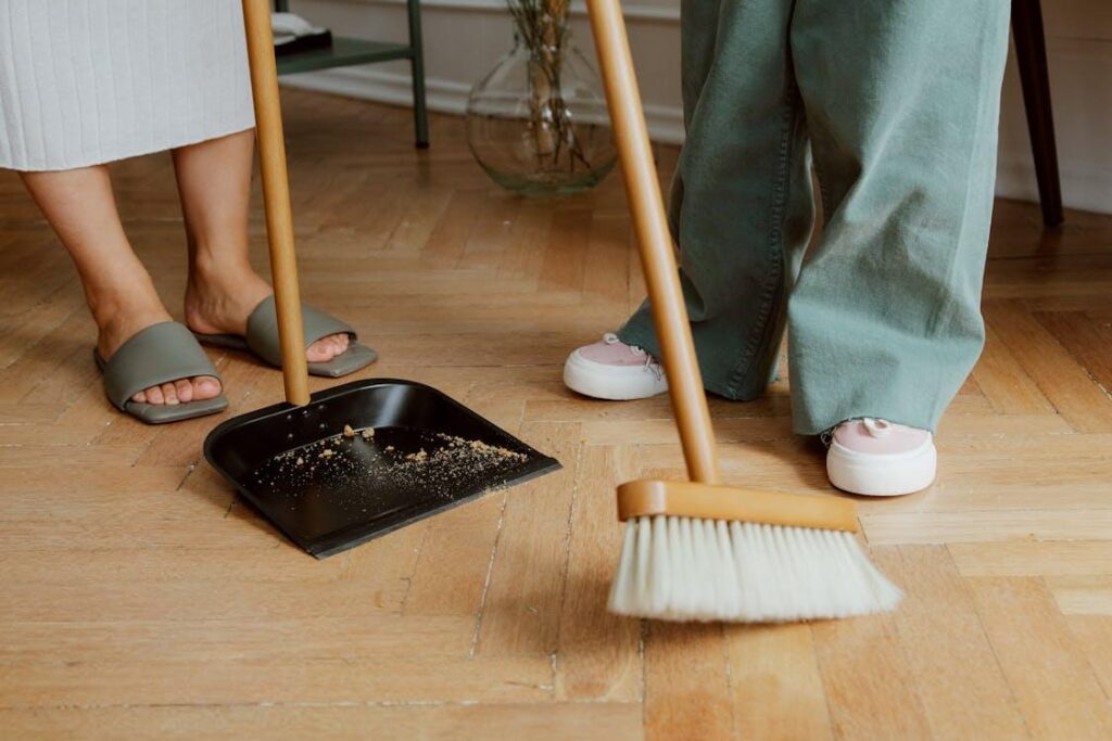 close-up of two people cleaning dust and mud off the wooden floor