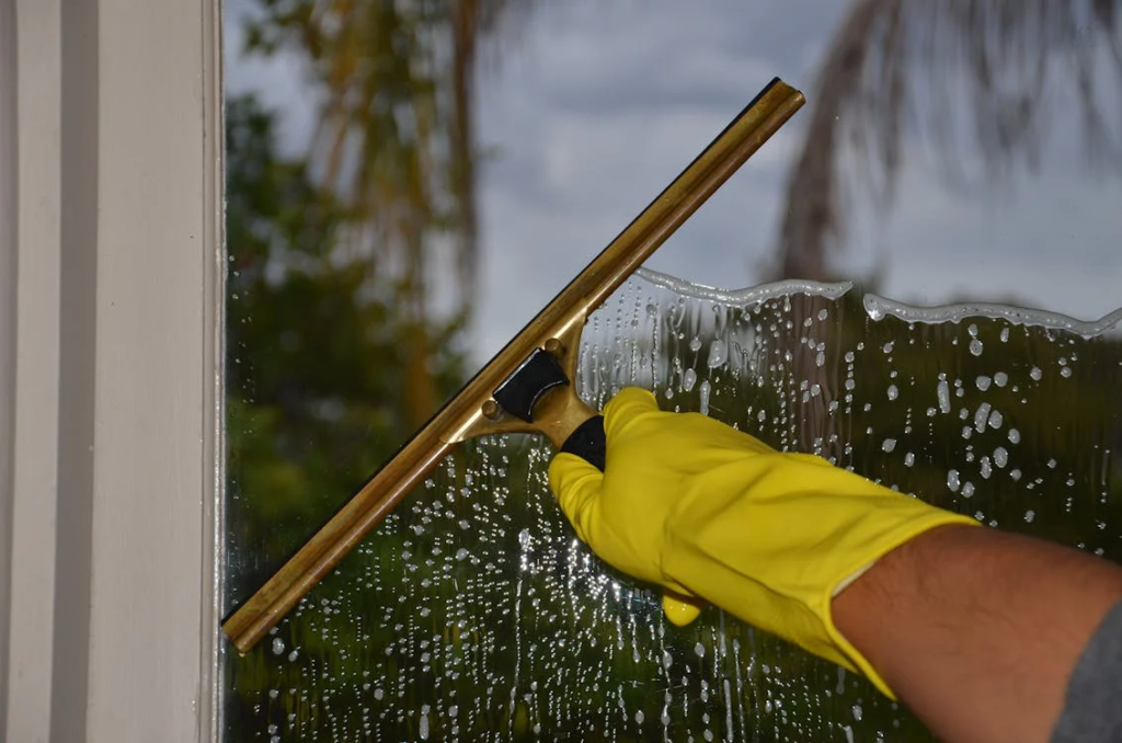 close-up of a person wearing gloves cleaning a window