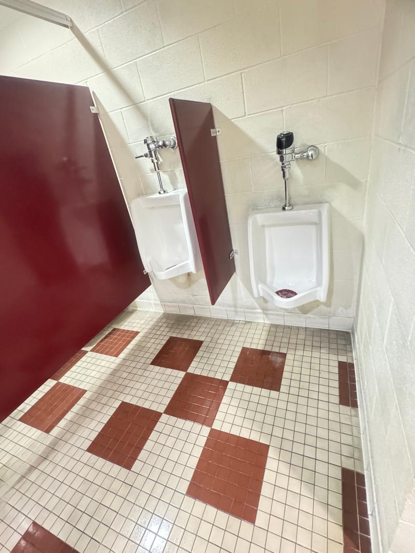 close-up of a stall in a restroom with tiled floor and dirty grout lines
